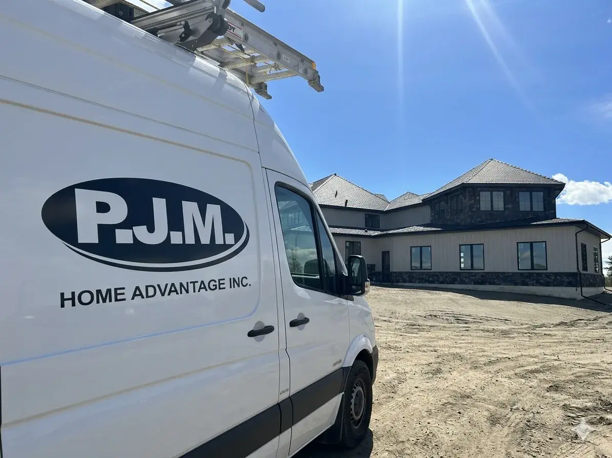 PJM Home Advantage company van parked at a new-build custom home in Central Alberta — ladder racks loaded, exterior finishing underway