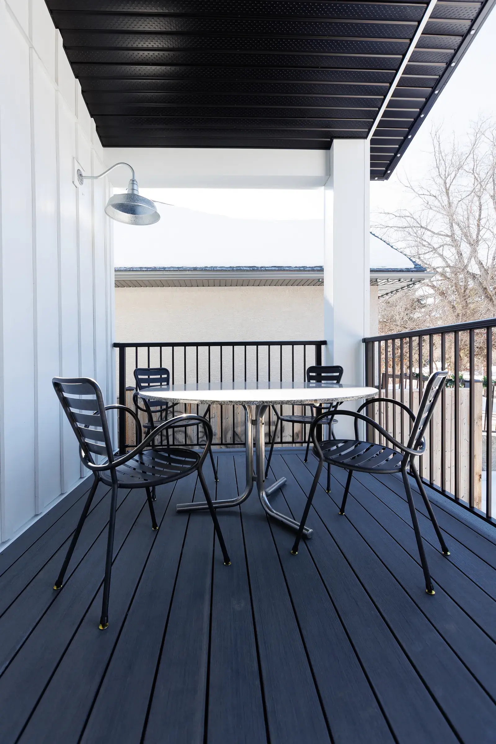 Covered deck detail on a Red Deer home with composite decking, black railings and a barn light, finished by PJM