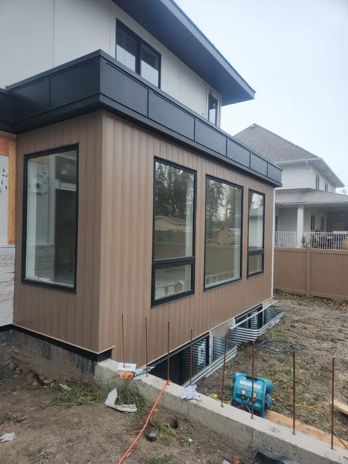 Custom-clad post-and-beam outdoor room structure on a high-end Central Alberta property, exterior cladding matched to the main house siding
