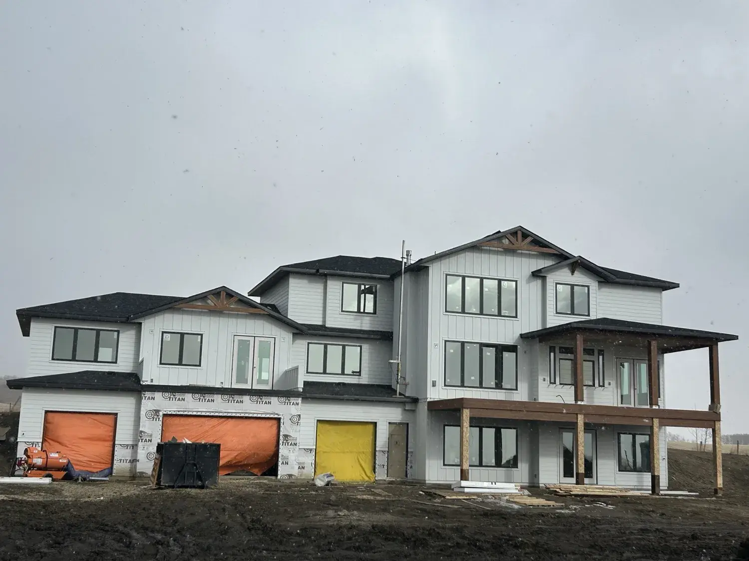 Steel roofing installation in progress on a large new-build home in Central Alberta — panel seams visible