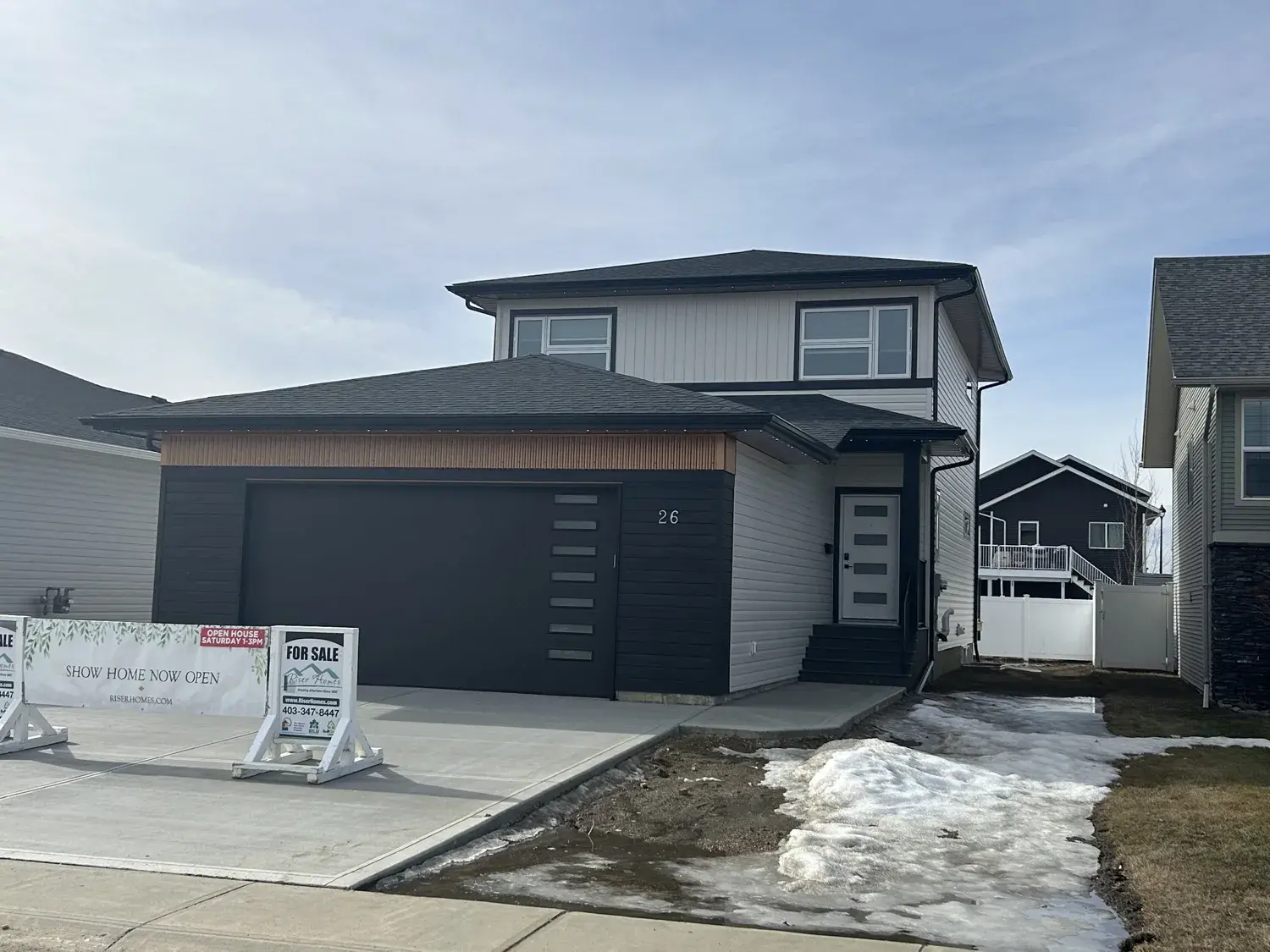 Finished standing-seam steel roof on a two-storey show home in Red Deer, Alberta — charcoal finish