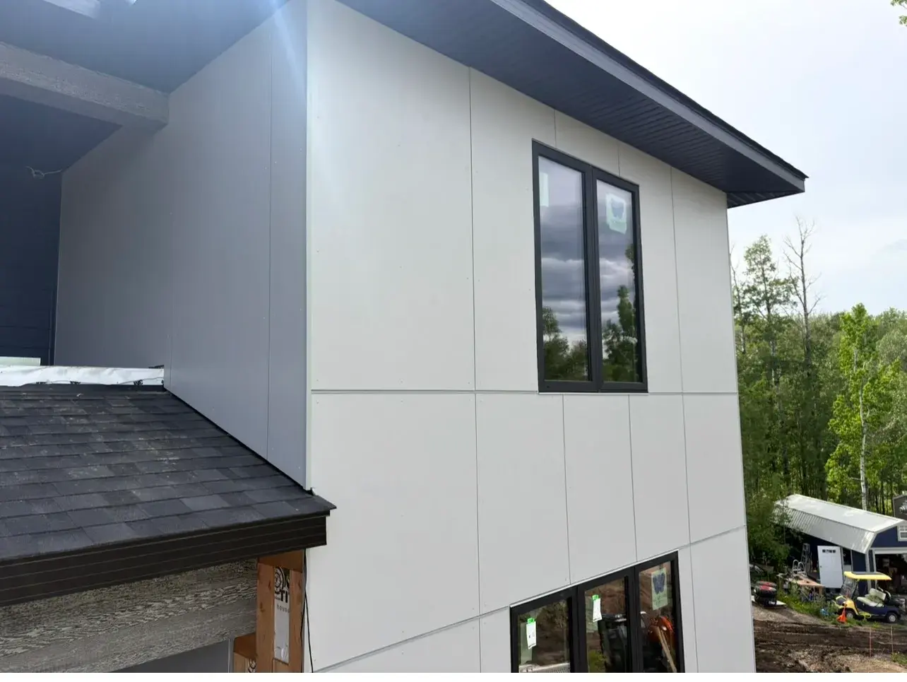 Detail of large-format grey panel cladding with clean black-framed window trim on a modern Sylvan Lake-area home by PJM